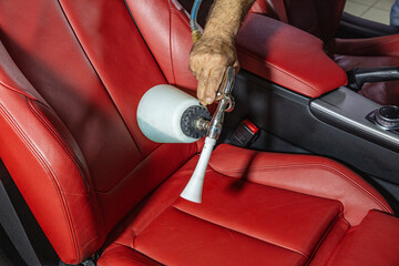 Professional chemical cleaning of car seats.Man cleaning car salon with disinfectant spray and cloth, close up.