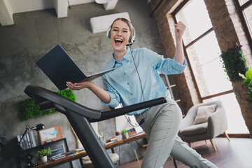 Photo of cheerful lucky lady recruiter dressed shirt earphones running treadmill winning device...