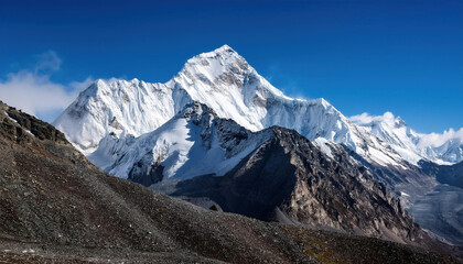 The snow-capped peaks of a majestic mountain and the surrounding mountains are seen together with the dark blue sky.