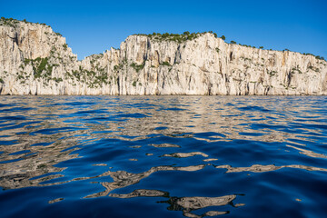 View from the Mediterranean Sea to the rocky coast of the Calanque National Park on a sunny summer day.