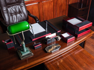 luxury desktop in the boss's office in a dark style. a lot of leather. banker  green lamp