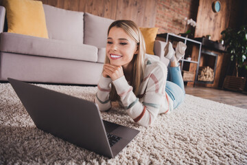 Young woman relaxing at home, smiling and enjoying leisure time with laptop in cozy living room setting