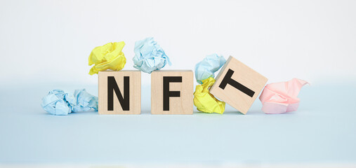 text of NFT on wooden cubes on the chart with crumpled colored paper