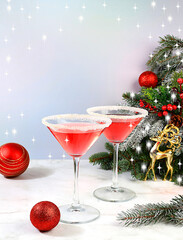 Christmas alcoholic cocktail martini in glasses on festive background with fir branches and decorations, bar concept and New Year's Eve, alcoholic drinks at party, selective focus.