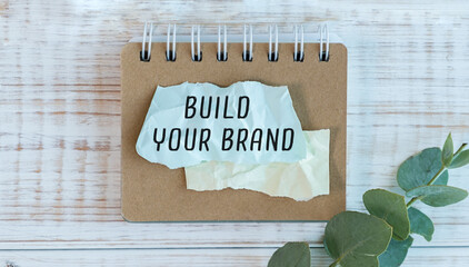 The word BUILD YOUR BRAND appearing behind torn brown paper.