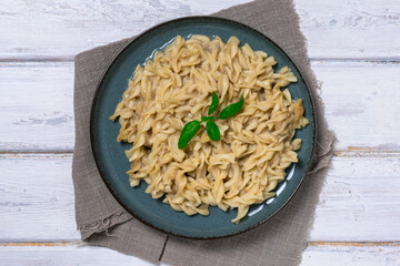 Pasta with Alfredo sauce. Italian pasta on a plate close-up, on a white wooden table.