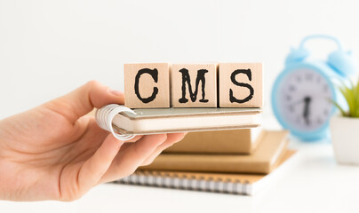 Business concept. On a white background, in the hands of a person, cubes with the inscription - CMS