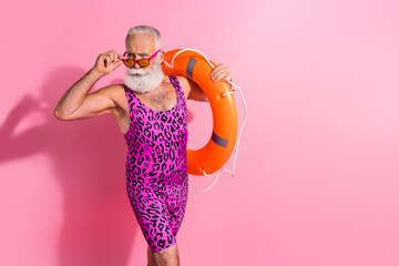 Photo of old man hold touch orange life buoy look sunglass wear swim suit isolated pink color background