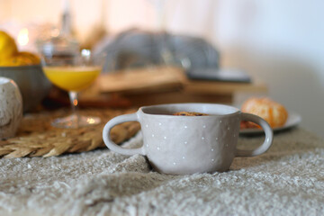 Books, e-reader, tea, orange juice, fruit, snacks, yarn, blanket and lit candles on the table....