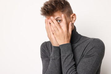 Portrait of scared young man on light background, space for text