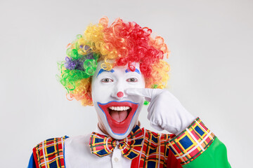 Emotional clown touching his nose on light background