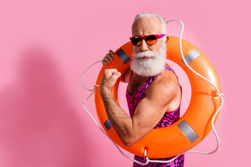 Photo of life guard man hold orange buoy ring show strength biceps wear dotted swimsuit isolated pink color background