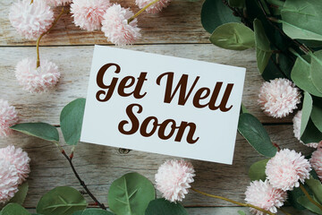 Get well soon text message with flower decoration on wooden background