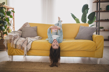Adorable preteen girl enjoying a playful moment upside down on a cozy yellow sofa