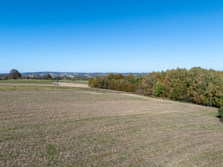 Obraz premium A vast agricultural landscape showcasing a clear blue sky, rolling hills, and a patchwork of fields ready for the next season. Nature's beauty and tranquility is captured here.