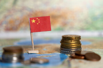 chinese flag and stacks of coins on a map background, symbolizing china's economy, financial...