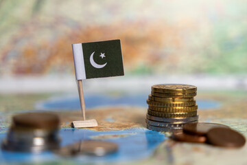 pakistani flag and coins on a world map, economy concept, representing finance, trade, and...