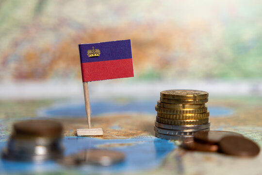 liechtenstein flag on map with coins, concept of finance, national economy, wealth, savings, stacks of money, and investment
