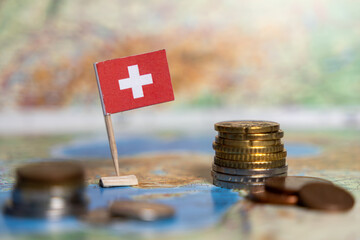 swiss flag with stacked coins on a map, financial concept, Switzerland economy, blurred background
