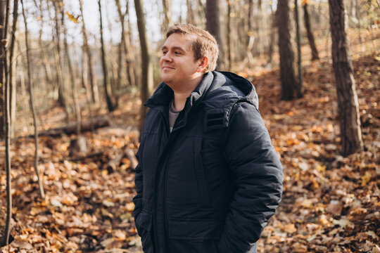30s Plus size male smiling outside on an adventure. Hiking, lifestyle, adventure and tourism concept. Young man standing in woodland, autumn time