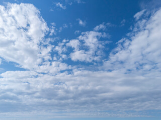 A clear blue sky filled with fluffy clouds creates a serene atmosphere, perfect for relaxation and...
