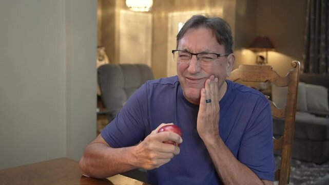 A man bites into an apple and has a toothache.  	