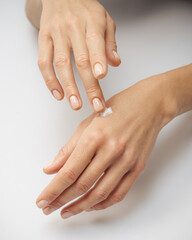 female hands apply cream one on top of the other on a white background