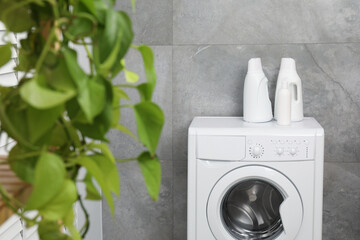 Different laundry detergents in bottles on washing machine indoors