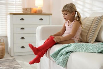 Little girl putting on soft tights at home. Space for text