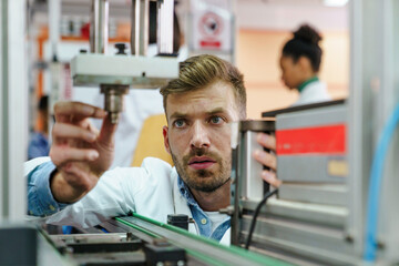 Fototapeta premium Mid Adult Scientist Fine-Tunes Robotics Equipment in Classroom