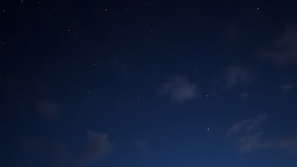 Fototapeta premium A magical night sky with faint clouds and subtle glowing stars on a dark navy background 
