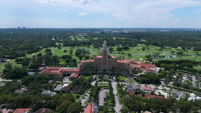Drone view of Biltmore Hotel located in Coral Gables, Miami. Historic building with central tower and sprawling wings, surrounded by lush greenery and golf courses