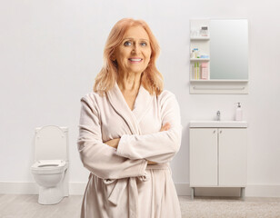 Mature woman in a bathrobe posing in a bathroom