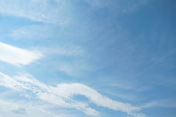 White fluffy clouds in the sky. Blue sky and cloud cover on a sunny summer day. Empty background, copy space