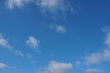 White fluffy clouds in the sky. Blue sky and cloud cover on a sunny summer day. Empty background, copy space