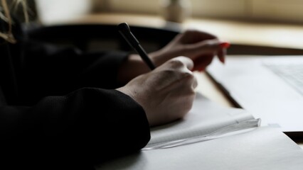 Woman Writing in a Notebook with Laptop Nearby