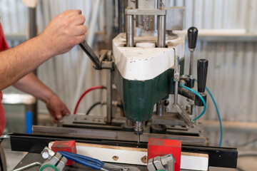 Primer plano de manos trabajando en máquina perforadora de aluminio