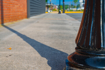 Lamp post base casting a shadow over an empty sidewalk in the small town of Ringgold, Georgia