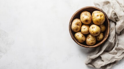 Obraz premium A bowl of freshly harvested potatoes rests on a white surface, highlighting their earthy beauty