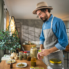 Side view of adult young man herbalist hold organic salve in workshop