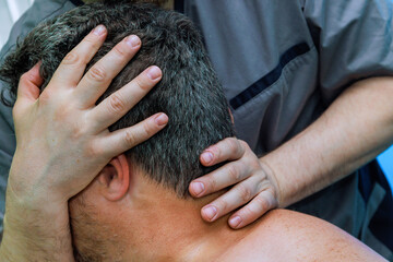 Massage therapist applies pressure to neck shoulders of client session takes place in massage spa environment, promoting relaxation healing.