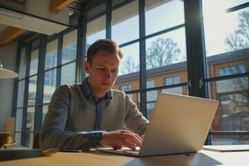 Fototapeta premium Man is sitting at a desk with a laptop open in front of him