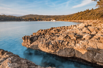 Rocky coastline meeting tranquil blue waters at sunset in the mediterranean sea