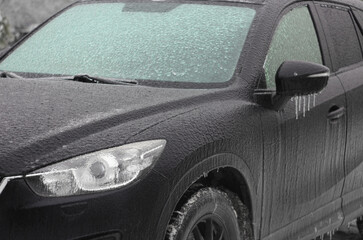 The car was iced over in winter after an icy rain. The windshield was covered with ice. Frost, rain...