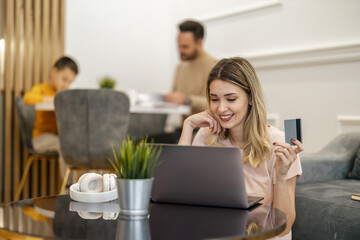 Woman Shopping Online While Family Enjoys Quality Time Together