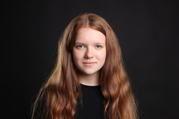 Naklejka premium Pretty red-haired teenage girl on black background