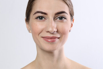 Beautiful young woman after henna eyebrows dyeing on light background, closeup