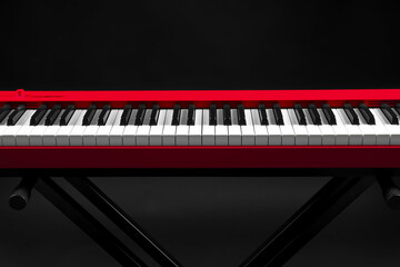 Red synthesizer on black background. Electronic musical instrument