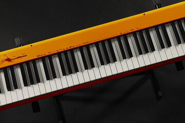 Orange synthesizer on black background, top view. Electronic musical instrument