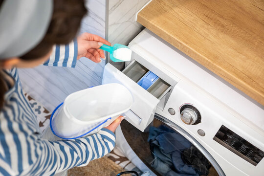 Woman housewife hands adding dry washing powder to washer machine laundry household routine